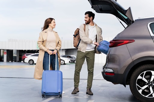 Couple Loading Luggage Into Airport Taxi
